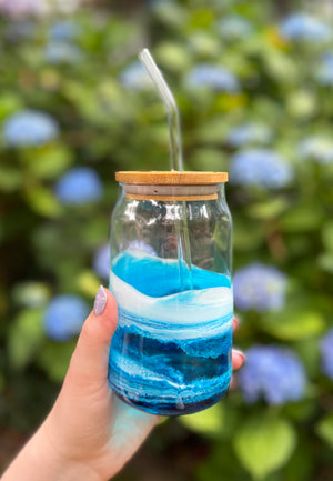 ocean inspired resin painted glass can cup held in womans hand outside