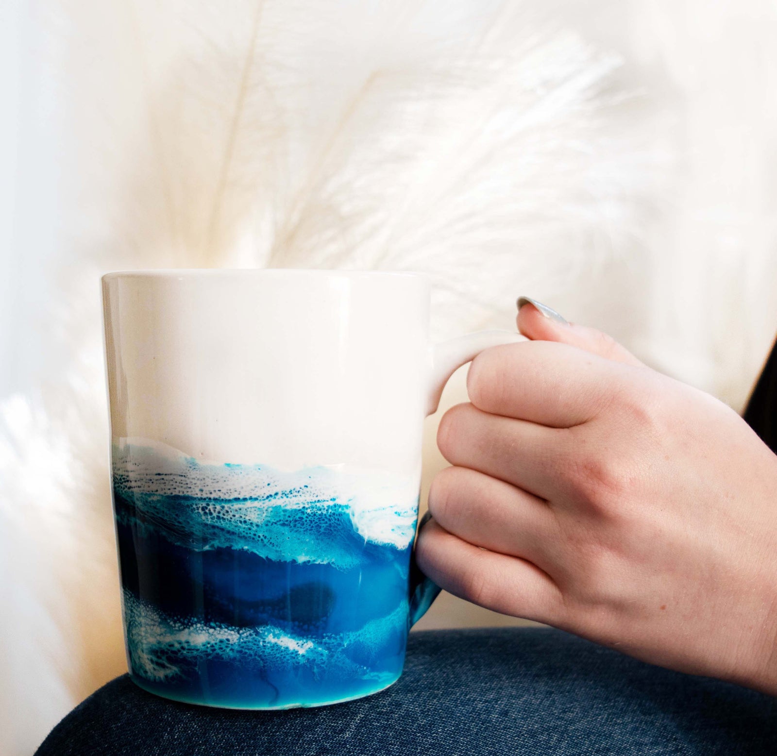white mug hand painted with ocean blue waves sitting on table